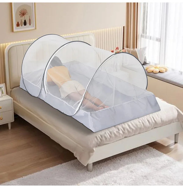 Une femme est installée dans une tente de lit moustiquaire qui est installée dans un lit. La chambre est classique dans les tons de beige.