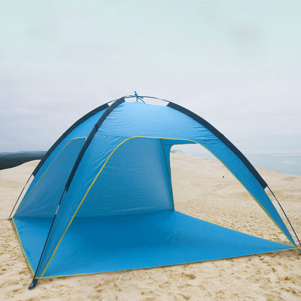 Une tente de plage bleue est posée sur du sable. Elle a trois côtés ouverts. 