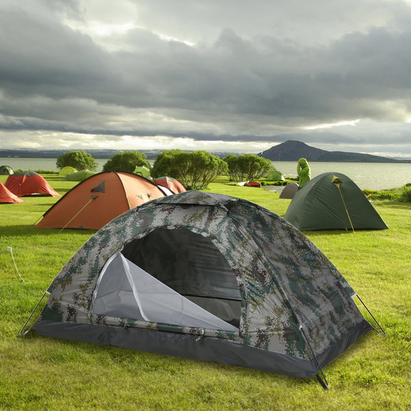 Une tente militaire anti uv est installé dans la nature entouré d'autres tentes.  La tente est pour une personne et a un motif vert camouflage.  
