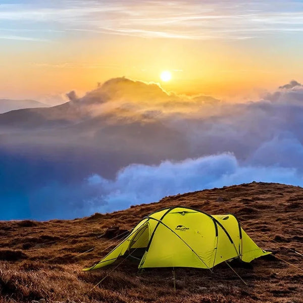 Une tente igloo légère verte fluo est posée au sommet d'une montagne. C'est une tente deux places.