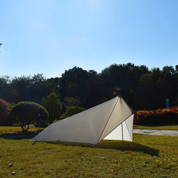 Une toile de tente grise ultra résistante et imperméable est installée dans un jardin. La toile de tente est grise. 