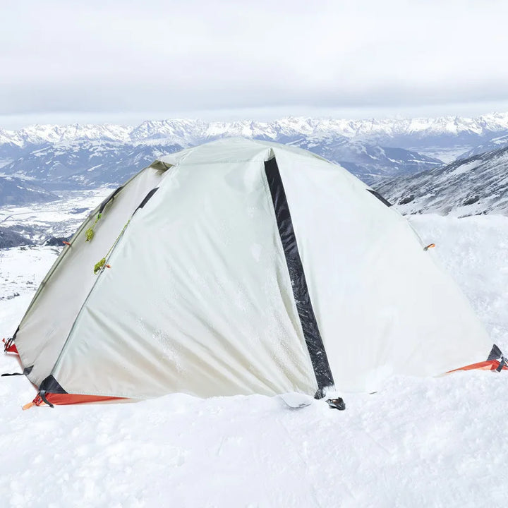 Une tente igloo est installée dans la neige. Elle est verte claire et est pour 2 personnes. 