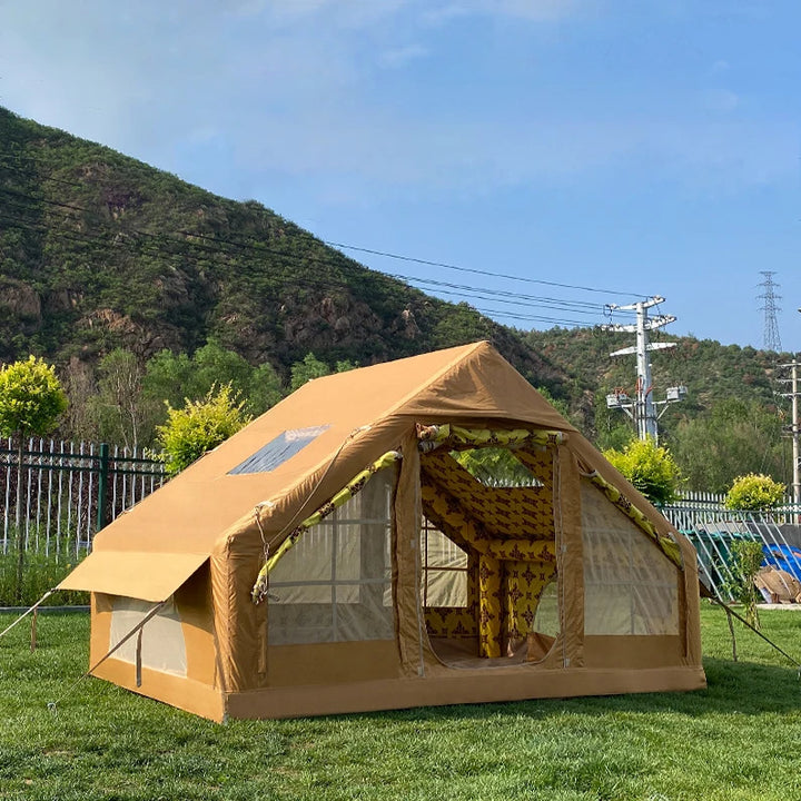 Une tente gonflable marron type marabout avec de nombreuses fenêtres et intérieur à motif est installée dans un jardin. Elle peut accueillir jusqu'à 8 personnes. 