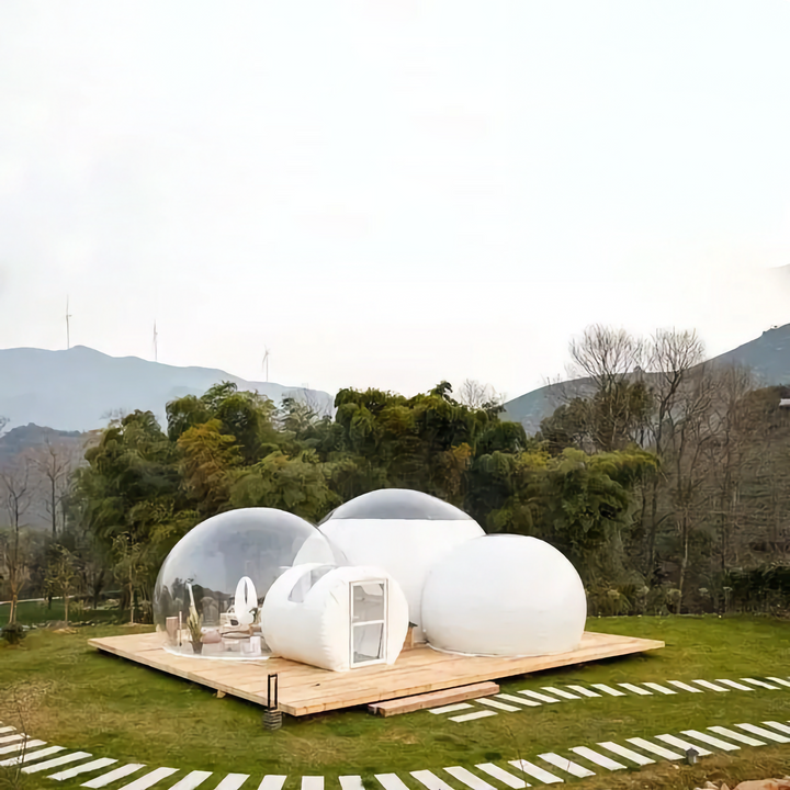 Une tente bulle transparente et blanche avec 3 bulles est installée sur une terrasse. Il y a deux chambres. 