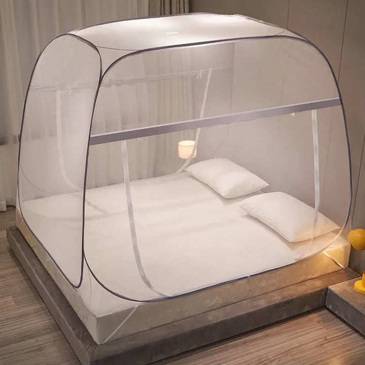 Une tente de lit moustiquaire est installée sur un lit. La décoration de la chambre est simple et moderne.