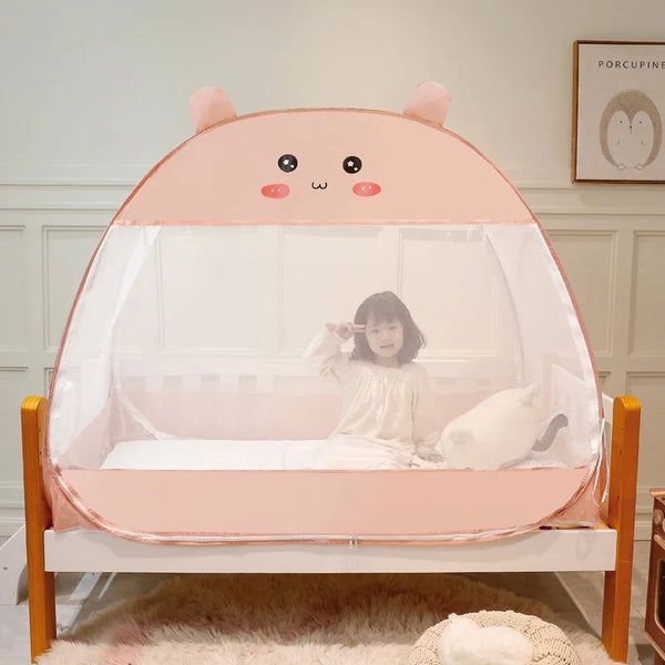 Une tente de lit moustiquaire rose avec des oreilles et un visage kawaï est installée dans une chambre d'enfant. La chambre a une déco blanche. 