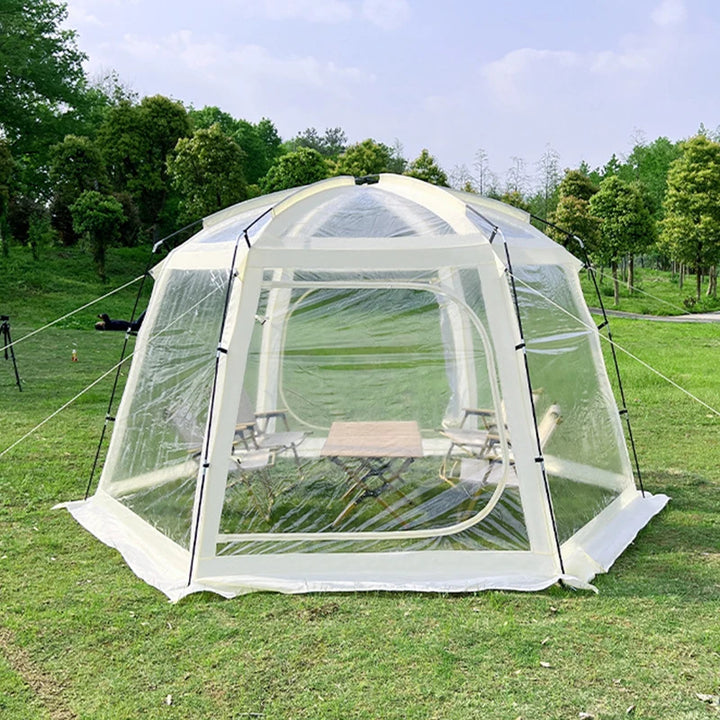 Une tente de réception en forme de dôme transparente est installée dans l'herbe. 