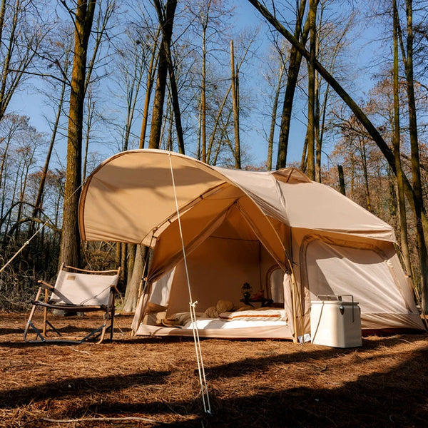 C'est une tente de glamping hexagonal. Elle est beige, plantée dans la forêt avec un siège devant. Elle a 5 places. 