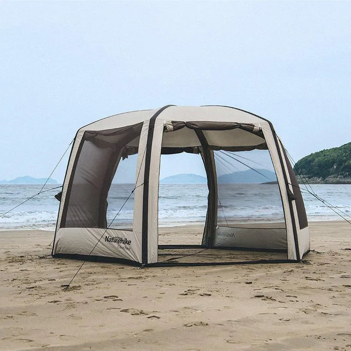 Une tente gonflable avec double porte et de grandes fenêtres sur chaque autre pan est installée sur une plage. La tente est beige.