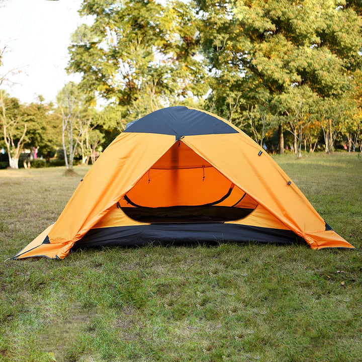 Une tente jaune de camping pour 2 personnes est installée sur une étendue d'herbe. Elle a une double porte. 