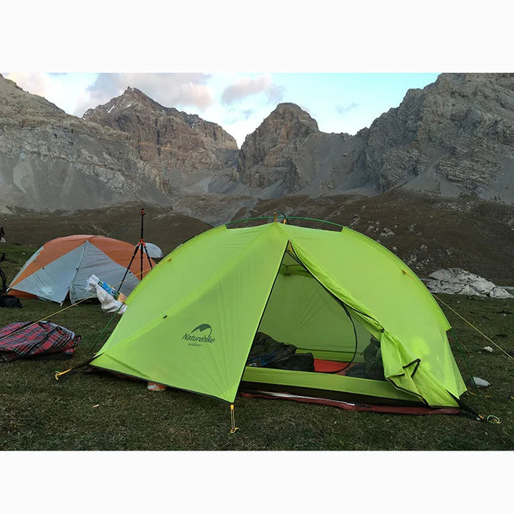 Une tente verte fluo est plantée au bord d'une montagne. Elle est verte fluo. 