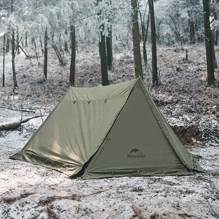 Une tente militaire verte est installée dans la forêt. Il a neigé. 